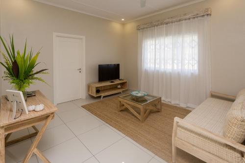 a living room with a couch and a television at Beau Vallon Villa Chalets in Beau Vallon