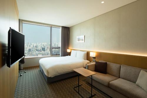 a hotel room with a bed and a couch at Sotetsu Hotels The Splaisir Seoul Dongdaemun in Seoul