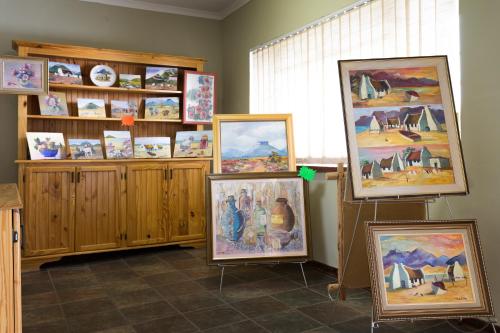 
a room with a painting on the wall and pictures on the wall at Colesview Guest House in Colesberg

