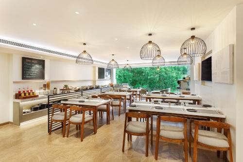 a dining room with tables and chairs and a kitchen at Ginger Mumbai, Andheri in Mumbai