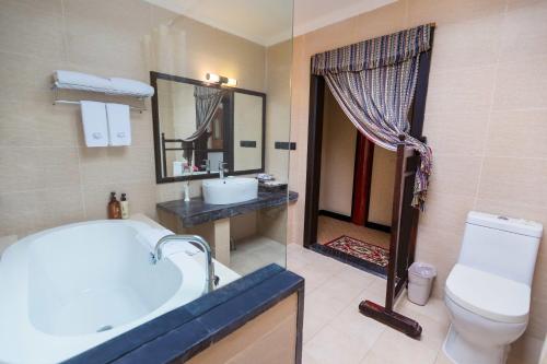 a bathroom with a tub and a toilet and a sink at Lijiang Wangfu Hotel in Lijiang