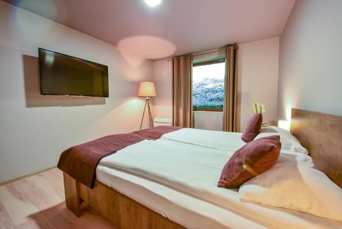 a bedroom with a large bed with a flat screen tv at Arsenal Park Transilvania in Orăştie