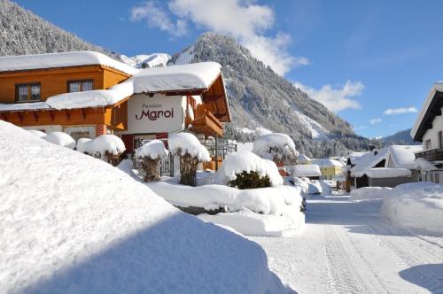 a house covered in snow next to a mountain at Hotel Maroi in Wald am Arlberg