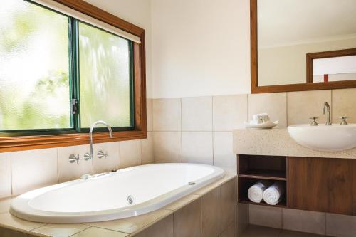 a bathroom with a tub, sink and mirror at Cable Beach Club Resort & Spa in Broome