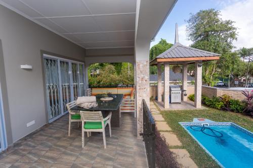 a patio with a table and a gazebo and a pool at Beau Vallon Villa Chalets in Beau Vallon