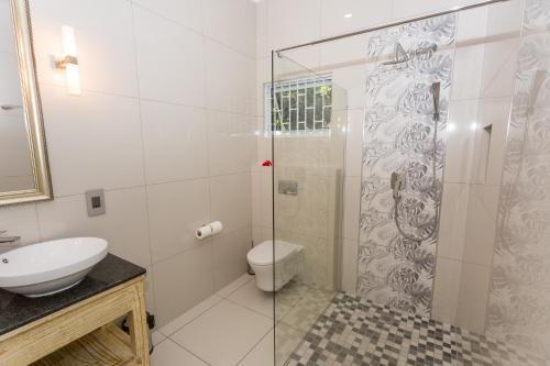 a bathroom with a shower with a toilet and a sink at Beau Vallon Villa Chalets in Beau Vallon