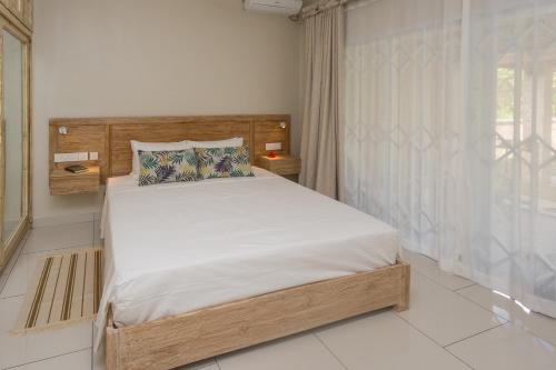 a bedroom with a bed with white sheets and a window at Beau Vallon Villa Chalets in Beau Vallon
