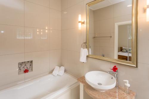 a bathroom with a tub and a sink and a mirror at Beau Vallon Villa Chalets in Beau Vallon