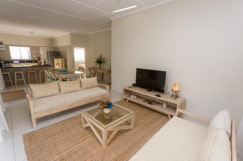 ein Wohnzimmer mit einem Sofa und einem TV in der Unterkunft Beau Vallon Villa Chalets in Beau Vallon