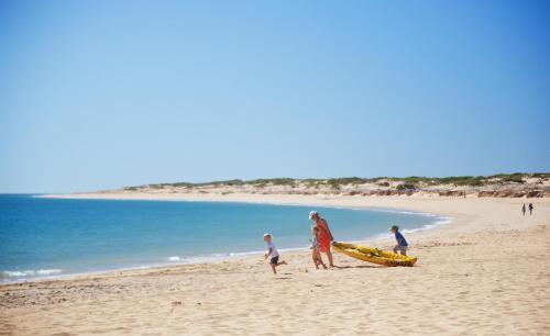 a group of people on a beach with a boat at Eco Beach Wilderness Retreat in Broome