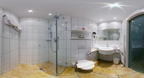 a bathroom with a shower and a toilet and a sink at Hotel Hirsch in Oberstaufen