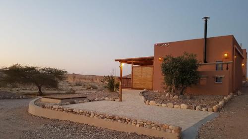 a building in the desert with rocks around it at Zman Arava in Zuqim