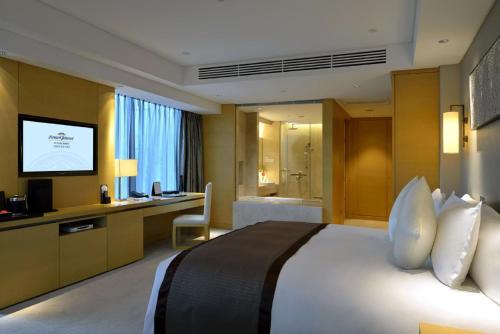 a hotel room with a bed and a television at Howard Johnson IFC Plaza Ningbo in Ningbo