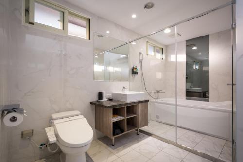 a bathroom with a toilet and a sink and a tub at Xianghe Hotel in Mingjian