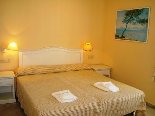 una camera da letto con un letto con due asciugamani sopra di Islantur Las Américas a Islantilla