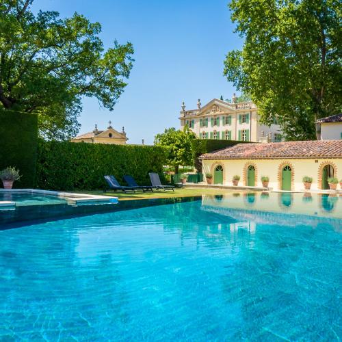 une piscine avec de l'eau bleue devant un immeuble dans l'établissement Chateau de Tourreau, à Sarrians