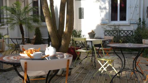 a patio with tables and chairs and a tree at Hôtel Savary in La Rochelle