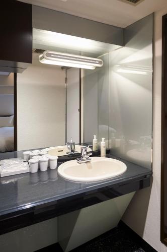 a bathroom with a sink and a large mirror at Hotel Consort Shin-Osaka in Osaka