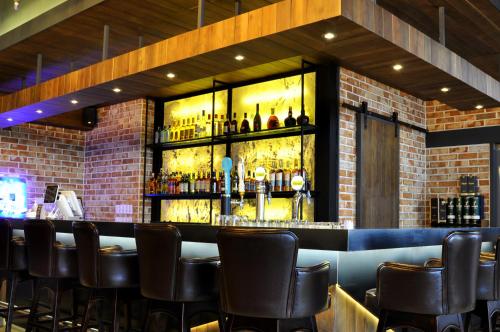 a bar with black leather chairs and a brick wall at Ocean Suites Jeju Hotel in Jeju