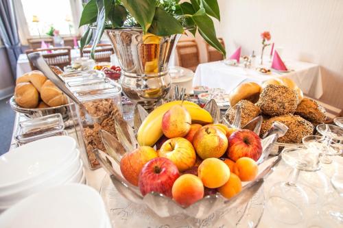 a table topped with a tray of fruit and bread at Hotel Rosenau in Bad Harzburg
