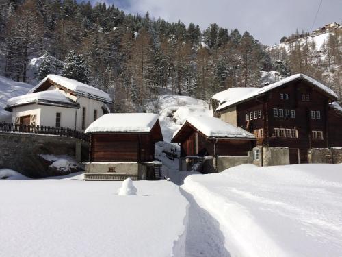 a snow covered house with a snow covered road at B&B Haus Granit Saas Grund in Saas-Grund