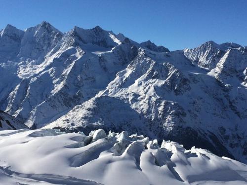 a snowy mountain range with snow covered mountains at B&B Haus Granit Saas Grund in Saas-Grund