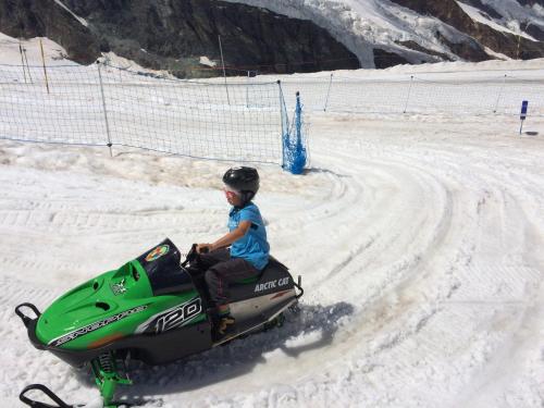 a young boy riding a snowmobile in the snow at B&B Haus Granit Saas Grund in Saas-Grund
