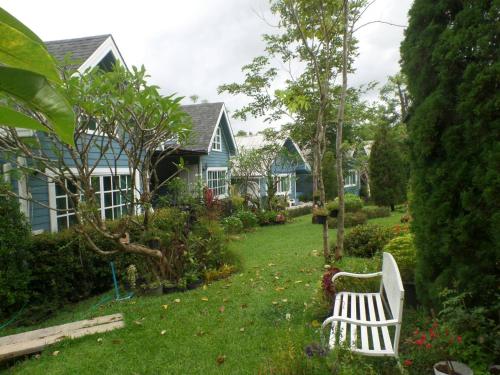 a white bench in the yard of a house at Baan JaoKorKluay บ้านเจ้ากอกล้วย in Chiang Rai