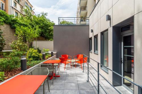 a patio with orange tables and chairs on a building at ibis budget Paris Clichy Mairie in Clichy