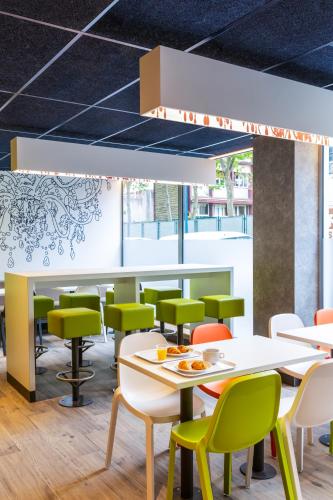 a restaurant with white tables and green chairs at ibis budget Paris Clichy Mairie in Clichy