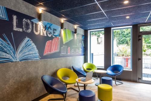 a waiting room with colorful chairs and tables at ibis budget Paris Clichy Mairie in Clichy