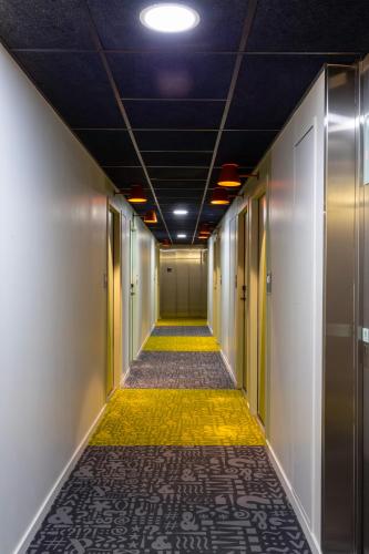 a long hallway with a yellow floor and a ceiling at ibis budget Paris Clichy Mairie in Clichy