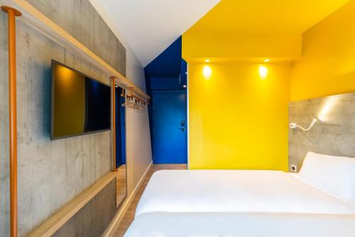 a bedroom with a bed with a yellow wall at ibis budget Paris Clichy Mairie in Clichy