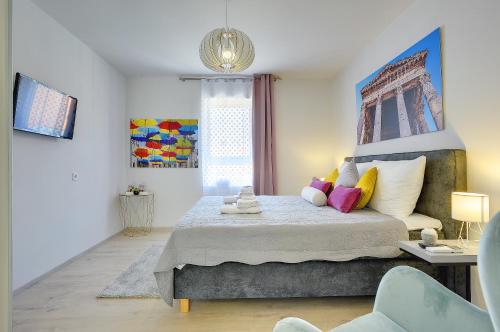 a bedroom with a king sized bed with colorful pillows at D&A Amphitheatre Apartments with free parking in Pula