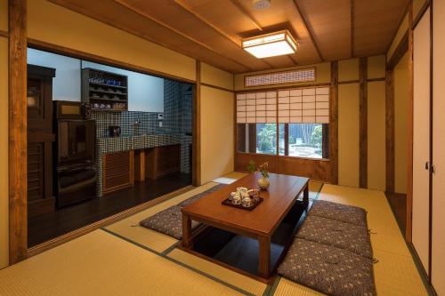 uma sala de estar com uma mesa e uma grande janela em Garaku an Machiya House em Quioto