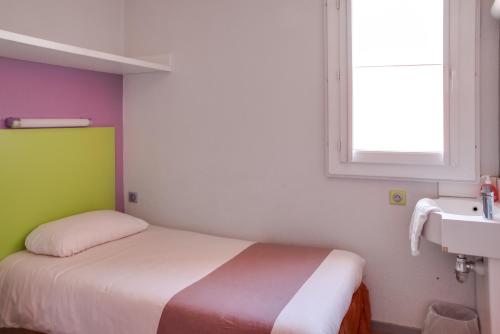 a small bedroom with a bed and a window at Hotel Valence Sud in Portes-lès-Valence