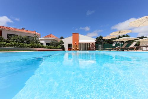 a large blue swimming pool with umbrellas at Sintra Rural Home - Cerrado da Serra in Sintra