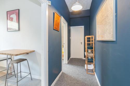 Rentalshosted Chorlton في مانشستر: مدخل مع جدران زرقاء وطاولة ومقعد