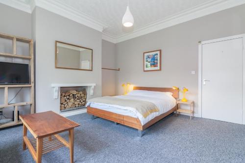 Rentalshosted Chorlton في مانشستر: غرفة نوم بيضاء مع سرير ومدفأة