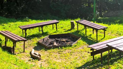 three picnic tables and a fire pit in a field at Osrodek Wypoczynkowy " BIESZCZADY" in Myczkowce