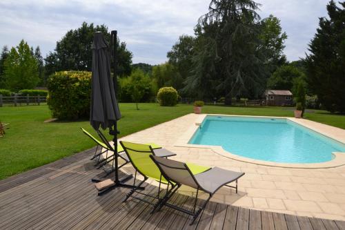 een terras met stoelen en een parasol en een zwembad bij Le Mathi in Fumel