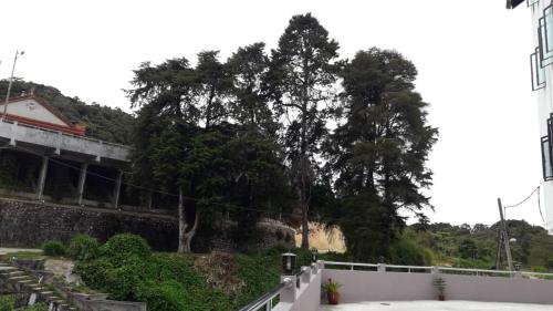 a white fence next to a building and trees at TULIP HOTEL & APARTMENT in Cameron Highlands