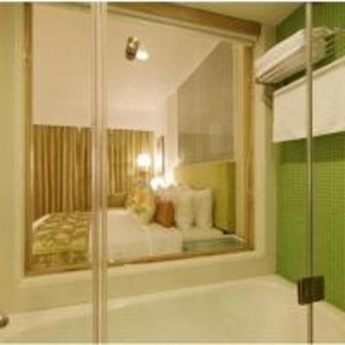 a bathroom with a glass shower with a bed at Yogi Executive, Navi Mumbai in Navi Mumbai