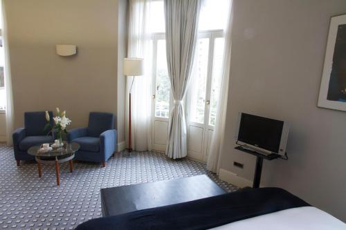 a hotel room with a bed and a tv and chairs at Gran Hotel Albacete in Albacete