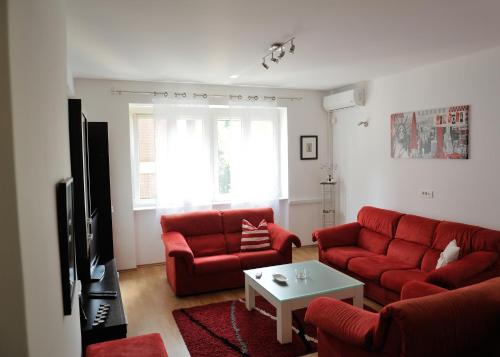 a living room with a red couch and a table at Apartment Sarajka Center in Sarajevo