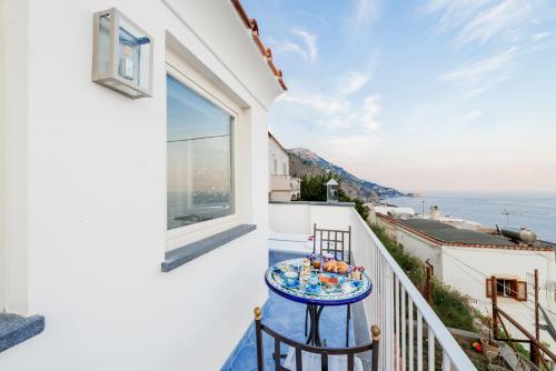een balkon met een tafel en uitzicht op de oceaan bij La Divina Amalfi Coast in Praiano