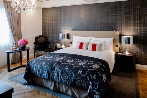 a bedroom with a large bed and a chandelier at Hotel Schweizerhof Bern & Spa in Bern
