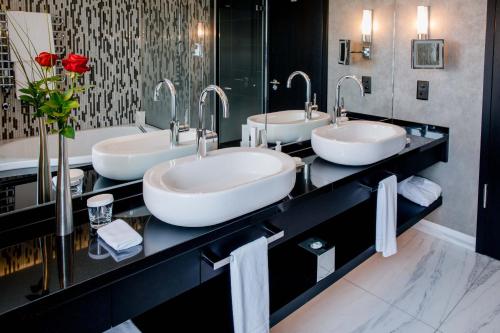 a bathroom with three sinks and a large mirror at Hotel Schweizerhof Bern & Spa in Bern