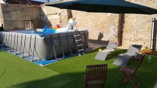 a pool with an umbrella next to a lawn with chairs at Appartement agréable 1 à 4 personnes in Chaumont