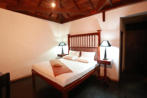 a bedroom with a bed with white sheets and two lamps at Villa Kusum in Hikkaduwa